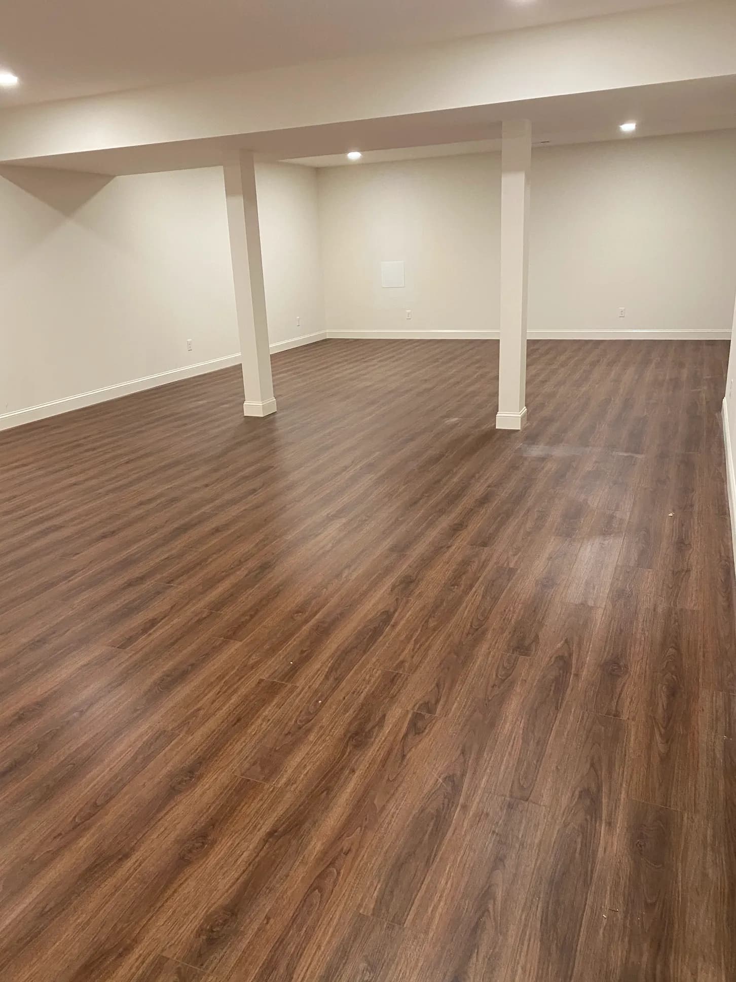 Dark wood-look LVP plank flooring in a finished basement — installed by Threshing Floors