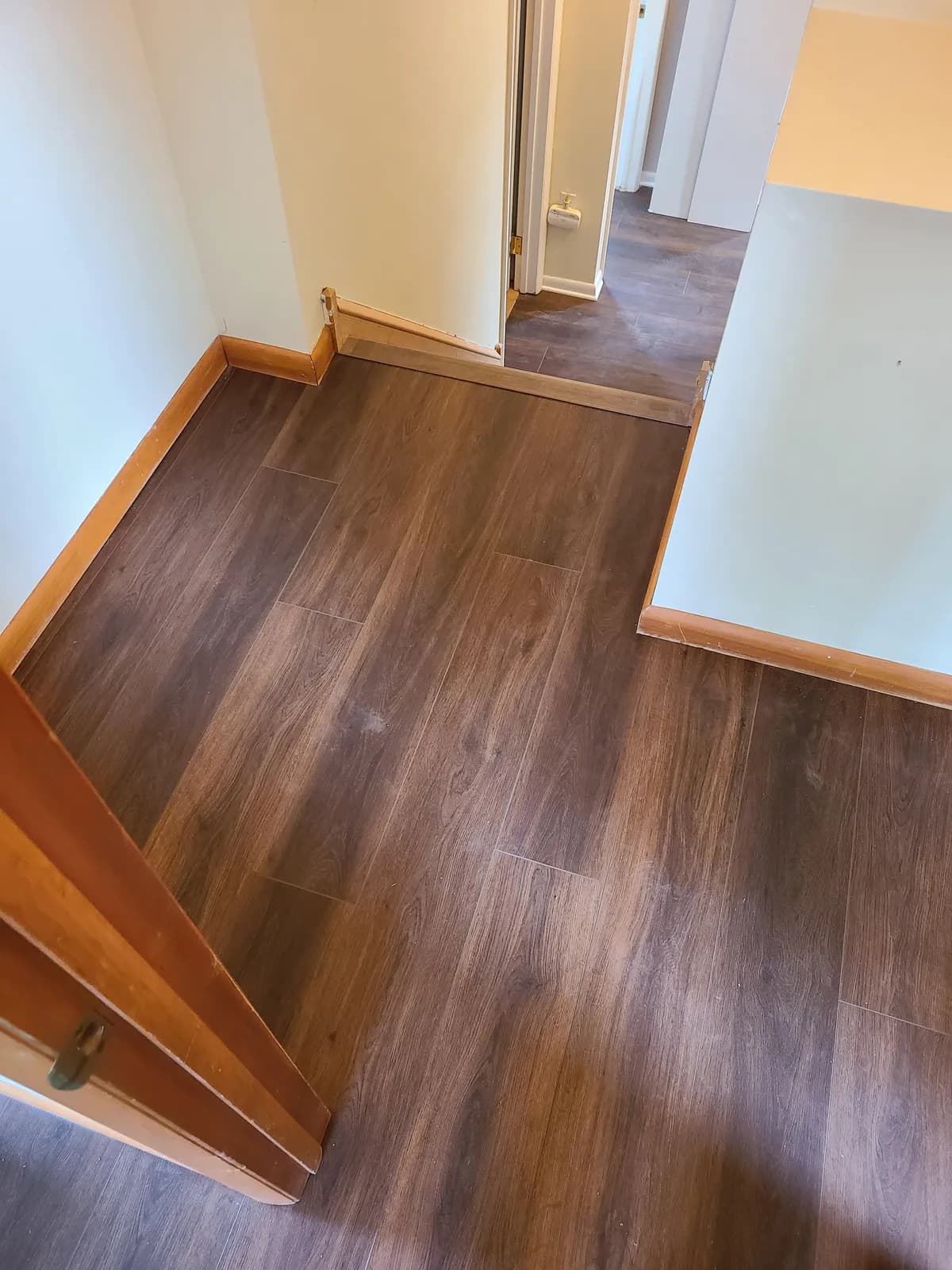Brown wood-look LVP flooring running through a hallway with doorway transitions — installed by Threshing Floors
