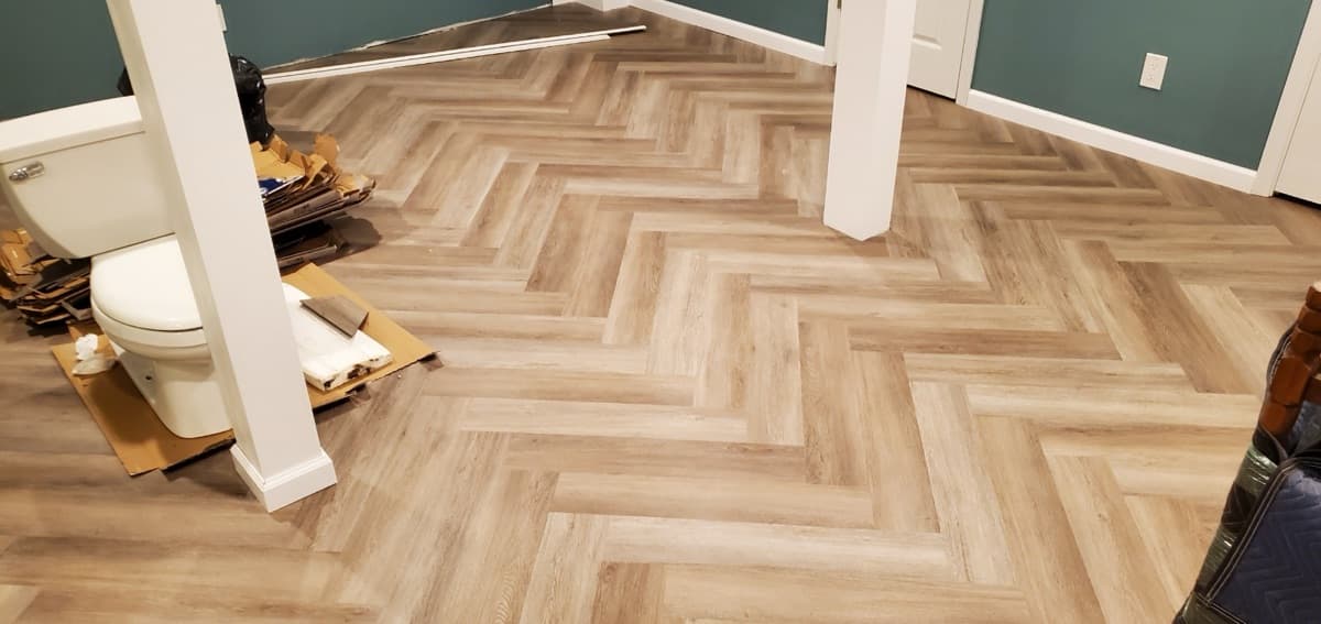 Herringbone LVP flooring detail showing pattern precision — installed by Threshing Floors