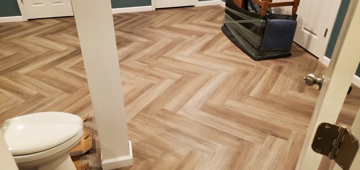 Herringbone pattern LVP flooring in a bathroom — installed by Threshing Floors
