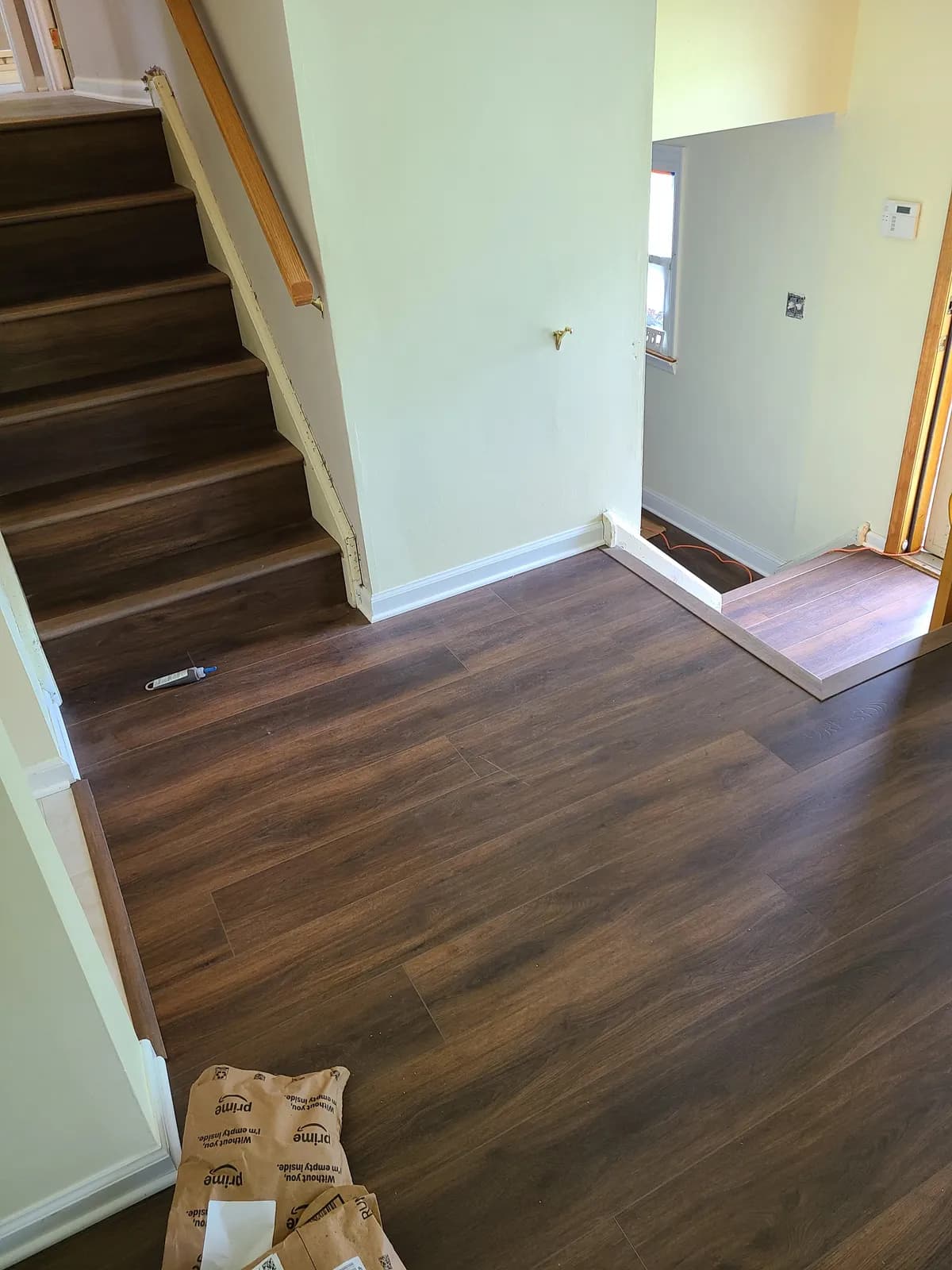Dark LVP plank flooring meeting the base of a staircase and landing — installed by Threshing Floors