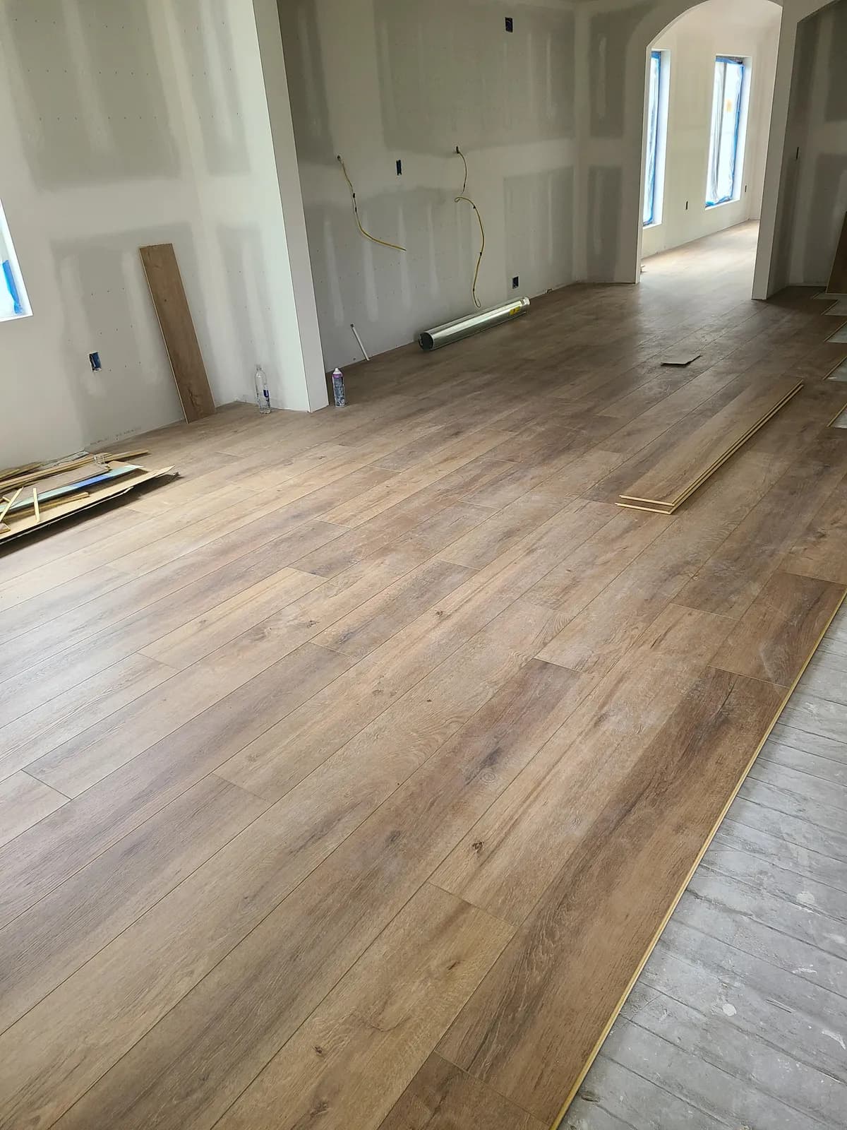 Wide-plank wood-look LVP being installed across a large open great room